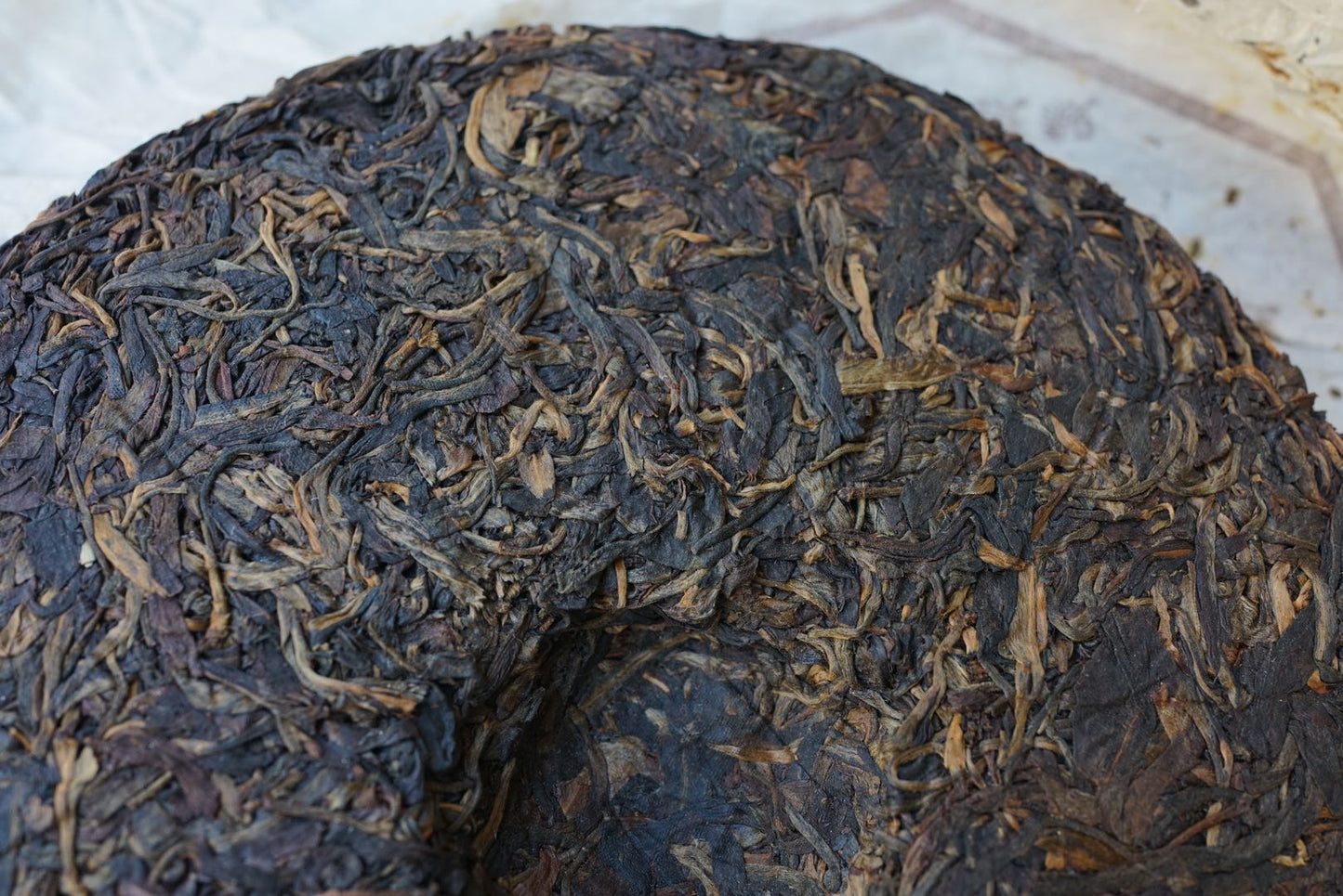 Detailed close-up of vintage 2004 Shun Shi Xing Yiwu Ancient Tree raw Pu-erh tea cake — aged Sheng Pu-erh 400g showing mature leaf structure, golden buds, and natural dry aging from Yunnan’s famous Yiwu mountain – Tea & Leaf.