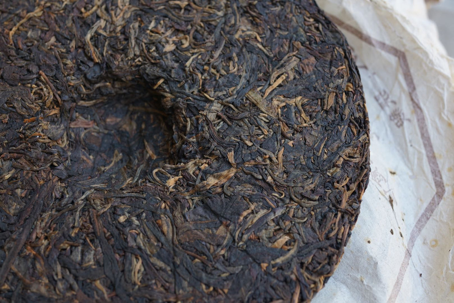 Close-up of vintage 2004 Shun Shi Xing Yiwu Ancient Tree raw Pu-erh tea cake — aged Sheng Pu-erh 400g showing dark fermented leaf texture, natural dry aging, and classic tight compression from Yunnan’s Yiwu mountain – Tea & Leaf