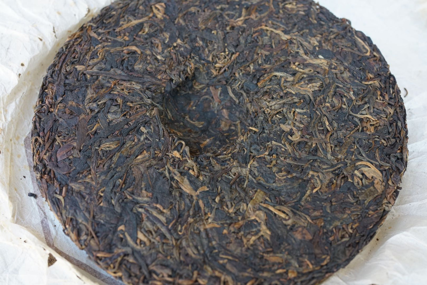 Vintage 2004 Shun Shi Xing Yiwu Ancient Tree raw Pu-erh tea cake — aged Sheng Pu-erh 400g with natural dry aging, showcasing tightly compressed tea leaves and rich dark patina from long-term storage – Tea & Leaf.