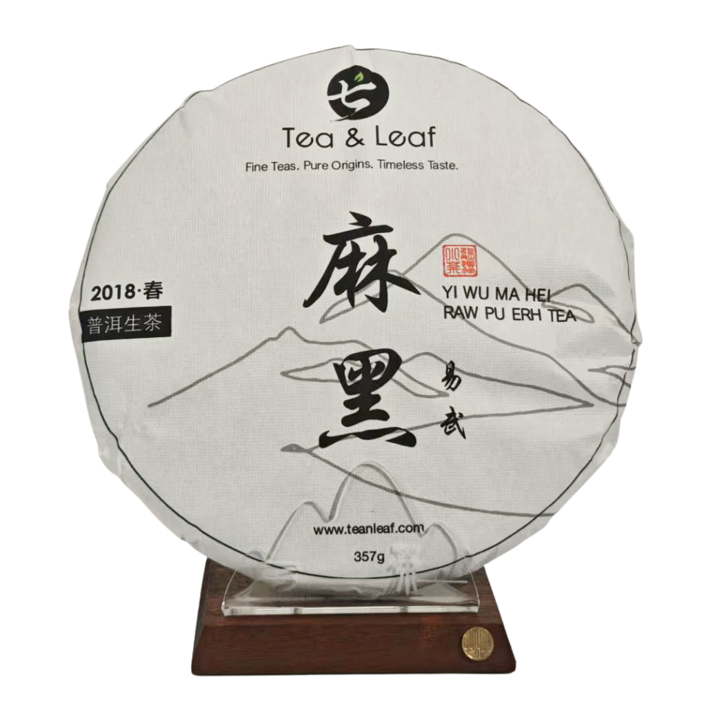 Tea & Leaf 2018 Spring Yiwu Mahei Ancient Tree Raw Pu-erh Tea 357g cake on wooden stand — premium Yunnan Sheng Pu-erh with smooth, full-bodied flavor and low bitterness.
