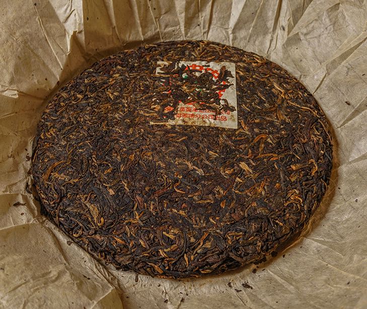 Unwrapped vintage 1995 private customized 8582 recipe Bulang Ancient Tree raw Pu-erh tea cake — aged Sheng Pu-erh showing rich leaf compression and golden tips from natural dry aging – Tea & Leaf.