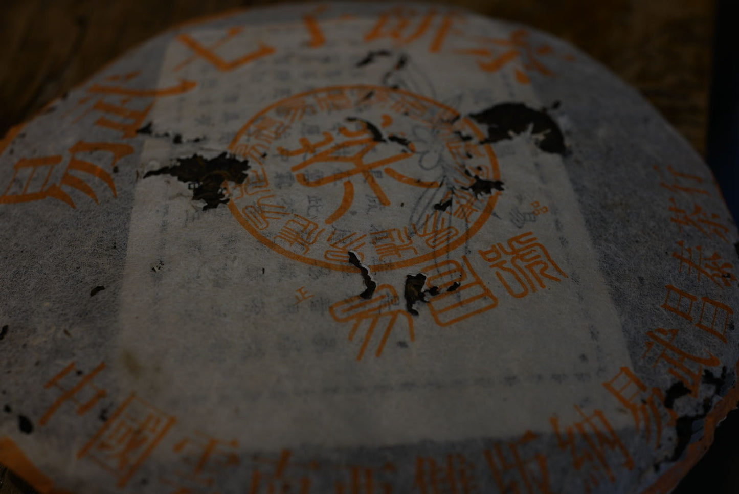 Close-up of 1999 Yichang Hao Songti vintage raw Pu-erh tea cake from Yunnan, aged Sheng Pu-erh with perfect dry storage and classic orange Song-style wrapper – Tea & Leaf.