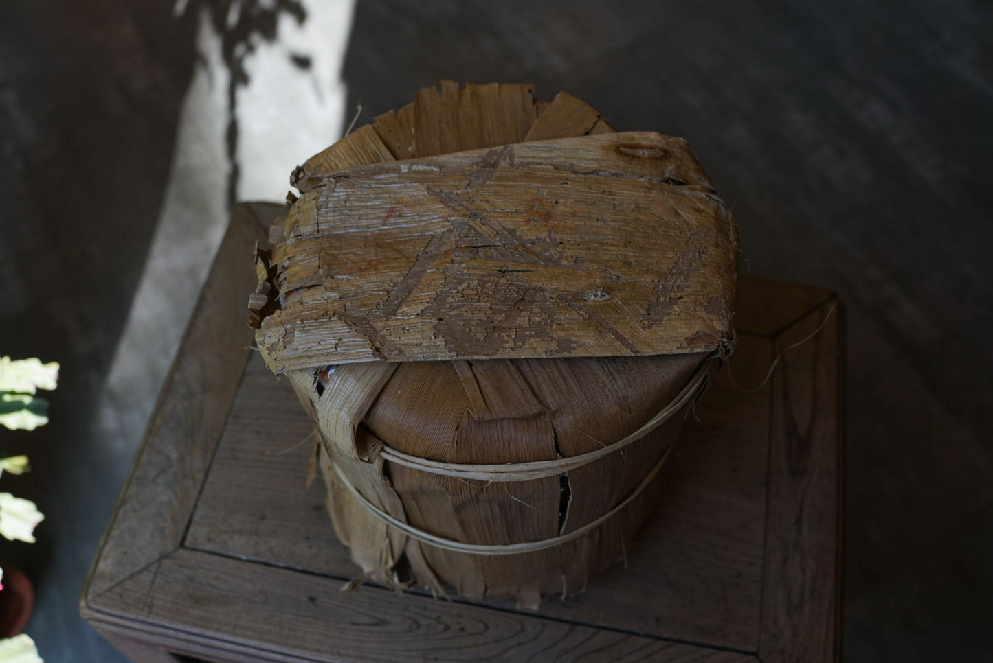 Vintage 1999 Yichang Hao Songti raw Pu-erh tea cake wrapped in original aged bamboo leaf packaging, showing natural patina and dry storage condition zoom out – Tea & Leaf.