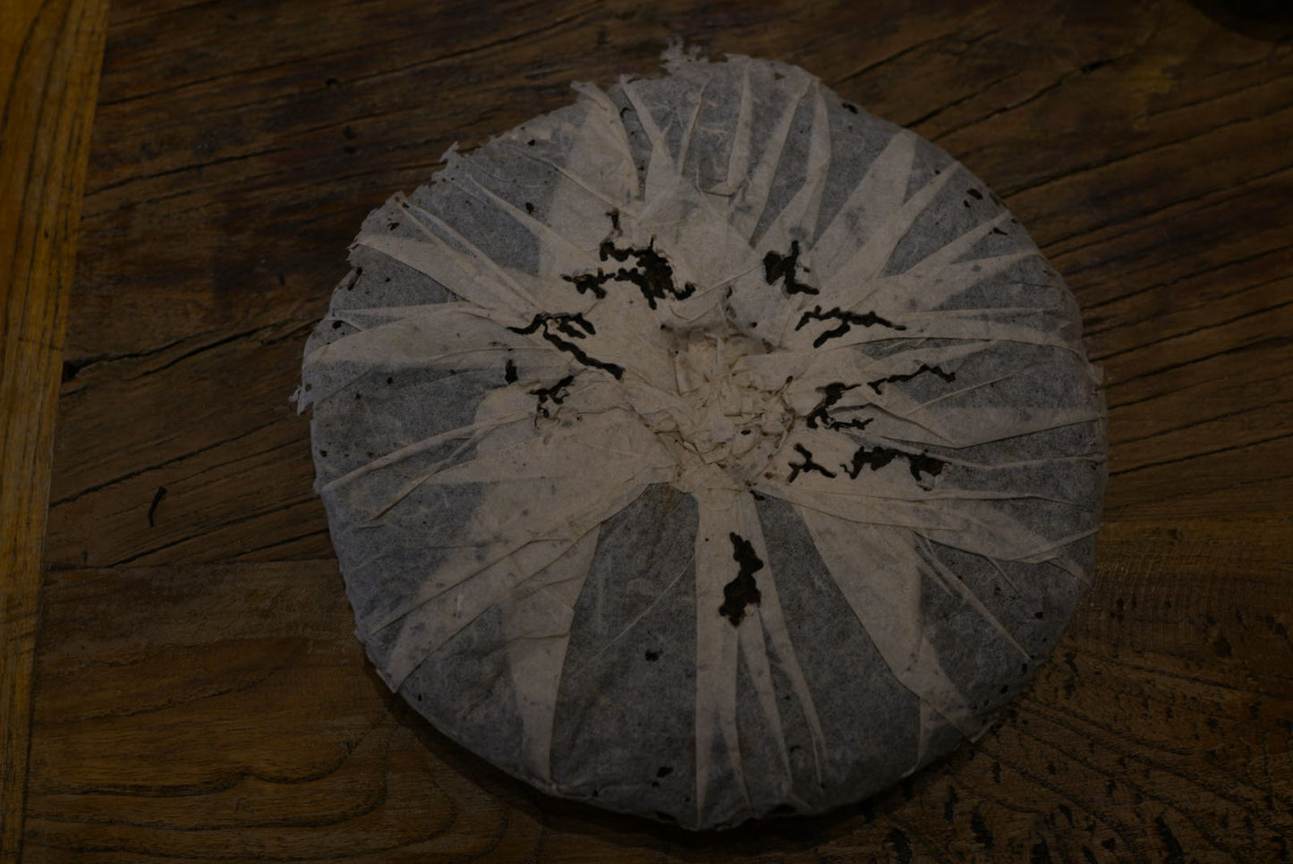 Back view of vintage 1999 Yichang Hao Songti raw Pu-erh tea cake, wrapped in aged paper with natural wear and patina from dry storage – Tea & Leaf.