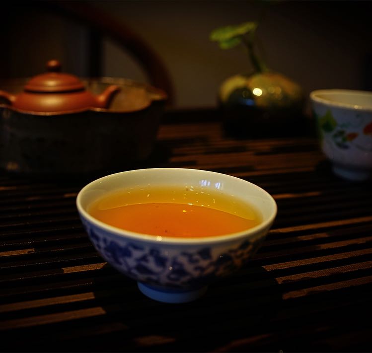 Brewed tea liquor from vintage 2004 Liming Tea Factory Ban Zhang Ancient Tree raw Pu-erh — aged Sheng Pu-erh showing amber-gold clarity and rich aroma in porcelain teacup – Tea & Leaf.