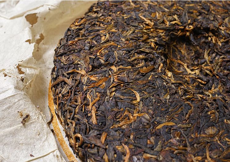 Close-up of vintage 2004 Liming Tea Factory Ban Zhang Ancient Tree raw Pu-erh tea cake — aged Sheng Pu-erh showing rich leaf texture, golden buds, and natural dry storage patina – Tea & Leaf.